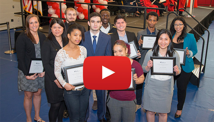 video still of students holding certificates with a play button over the image