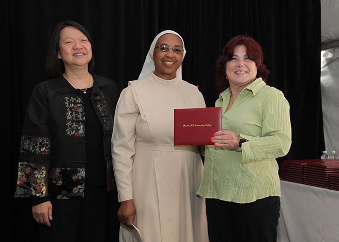female student receives diploma from Toni and president eddinger 