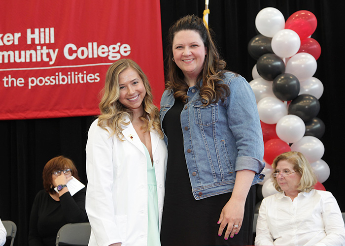 female student posing with faculty after getting her pin