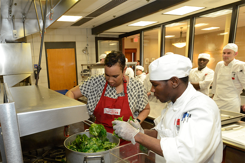 Elle-Simone instructing a student in the culinary art kitchen