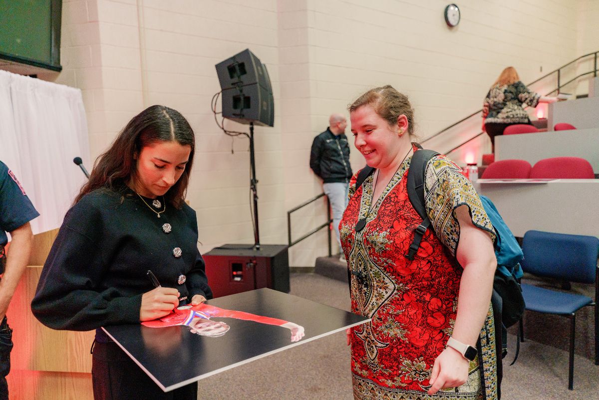 Aly signing a poster