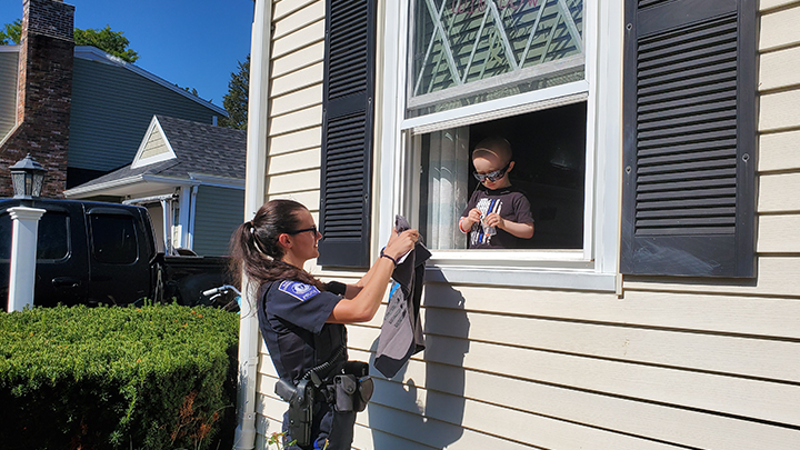 A cop giving a gift to a kid through a window.