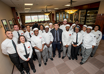 Jose Vargas posing with the students of the culinary arts dining room